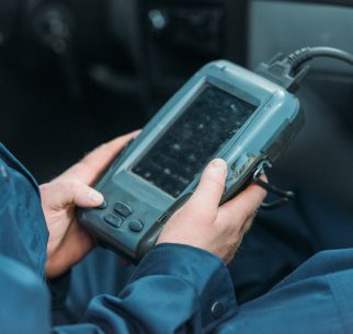 An automechanic using a car diagnostic tool in a service workshop.