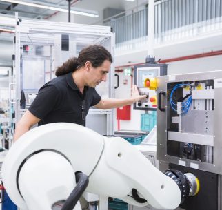 Man with assembly robot in factory
